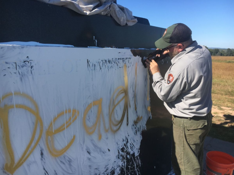A NPS Official removes the vandalism.